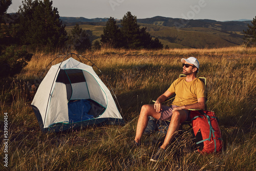 Man camping in nature, unpacking and packing small tent outdoors, recreation and hobbies.