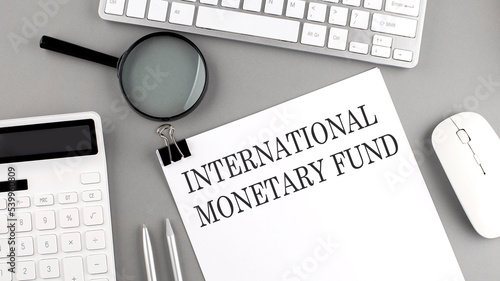 INTERNATIONAL MONETARY FUND written on paper with office tools and keyboard on the grey background photo