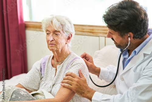 Seniorin wird vom Arzt mit dem Stethoskop untersucht photo