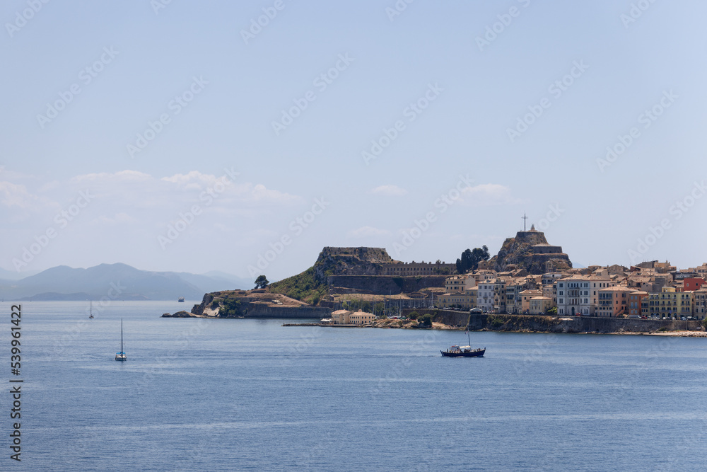 Naklejka premium Little sail and motor boats on the sea ripple in the port of Corfu city against the backdrop of Old Fortress, Kerkira, Ionian islands