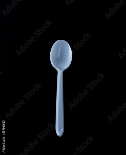 Disposable white plastic spoon and black background.