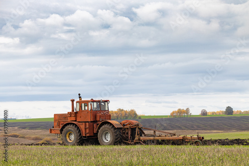 big old model tractor plows the ground.