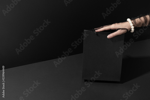 Lady hand holding blank shopping bag in studio closeup. Black Friday great sales offers. Discount holiday for customers and buyers (ID: 539964449)