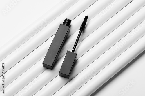 Open tube of mascara on white pipes in studio upper view. Decorative cosmetic product for eyelashes care. Professional makeup promotion (ID: 539964493)