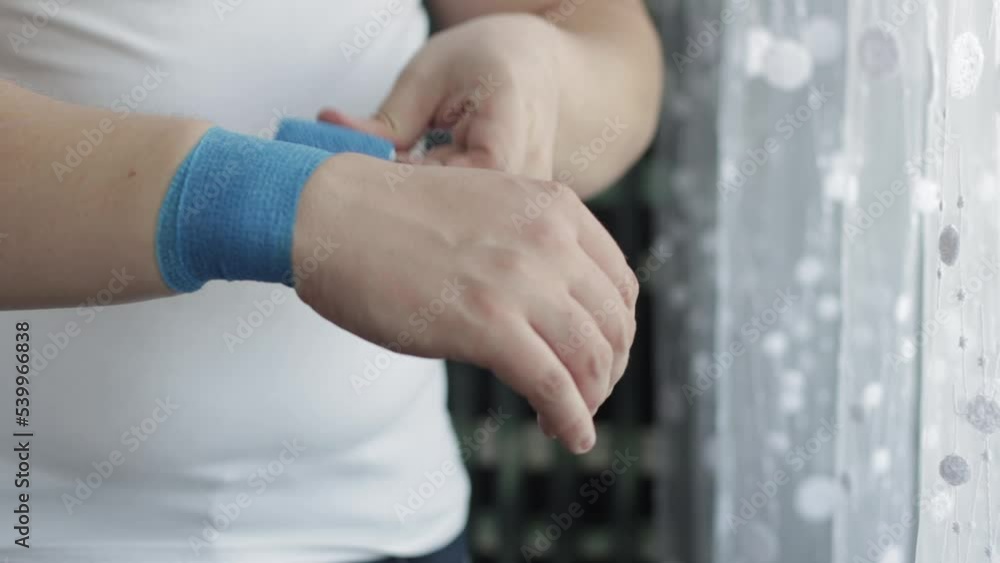 A man bandages his wrist with an elastic bandage on his arm with carpal tunnel syndrome and