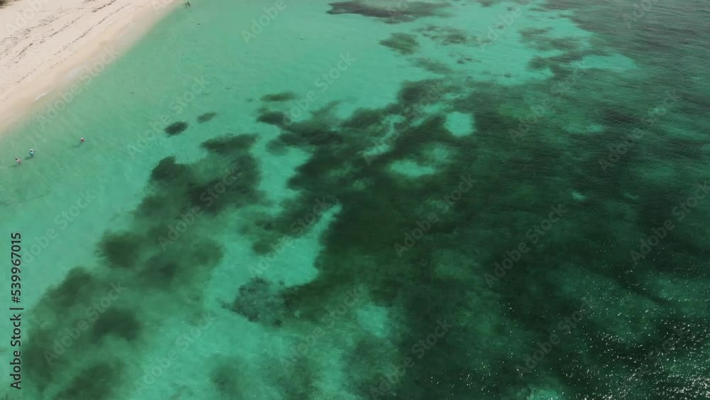 Tilt up shot revealing beautiful Mexican island through turquoise water and revealing white sand beach alongside seashore