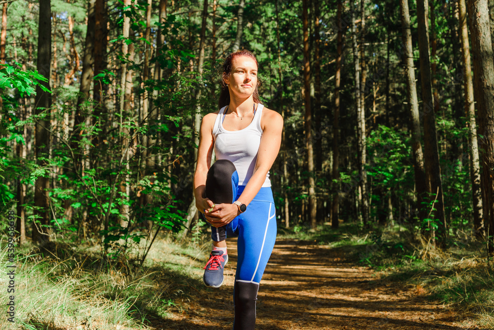 Young caucasian woman runner stretching legs before running in the summer park. Healthy workout woman jogging outdoors. Young caucasian woman runner stretching legs before running in the summer park. Healthy workout woman jogging outdoors.