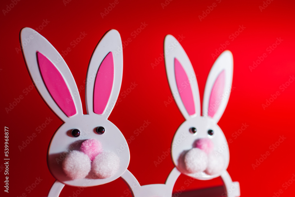 Fototapeta premium Two Toy Rabbit Bunny symbol of new year 2023 on red background.Christmas or New Year concept.Copy space.