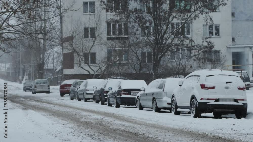 column of cars parked in the city in the yard under a layer of snow in a snow storm. Slippery road, parking column of cars parked in the city in the yard under a layer of snow in a snow storm. Slippery road, parking