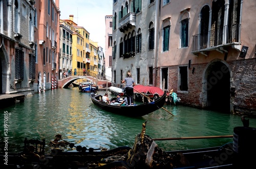 back view of a female gondolier driving a gondola in a canal in Venice