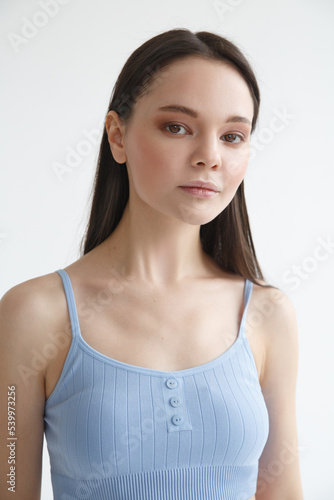 A cute girl in a pale blue tracksuit on a light  background.