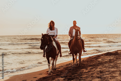 A loving couple in summer clothes riding a horse on a sandy beach at sunset. Sea and sunset in the background. Selective focus  © .shock