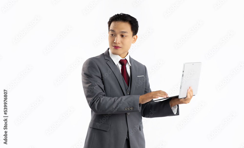 Asian businessman in grey suit red tie standing holding and using laptop computer on white background.
Asian businessman in grey suit red tie standing holding and using laptop computer on white background.