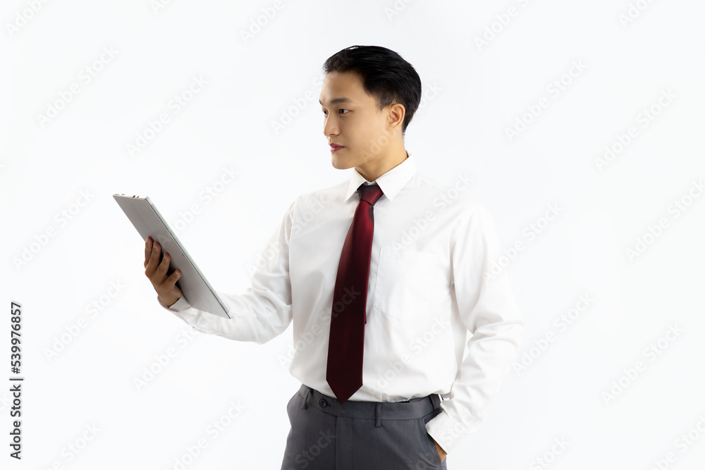 Asian man in white shirt red tie holding tablet computer looking and reading white background.
Asian man in white shirt red tie holding tablet computer looking and reading white background.