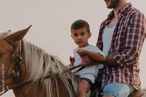 Father and son enjoy riding horses together by the sea. Selective focus  © .shock
