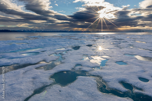 Sunburst over fast ice in Lancaster Sound, between Devon Island and Baffin Island, Nunavut, Canada photo