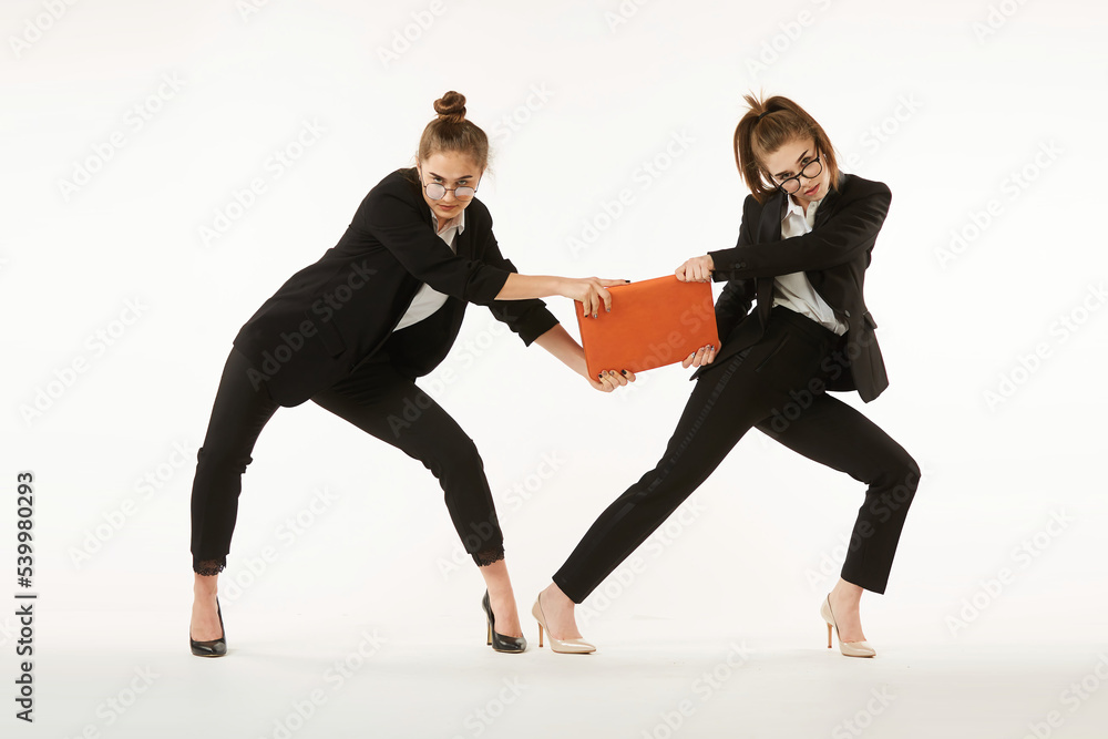 The competitive struggle of two girls in office clothes. Pure white background. The concept of business and corporate relationships in the enterprise.