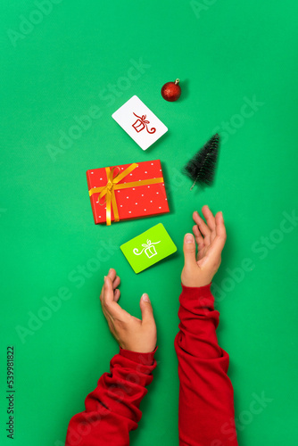 Minimal green background, gift box, bonus and discount cards and Christmas objects in female hands