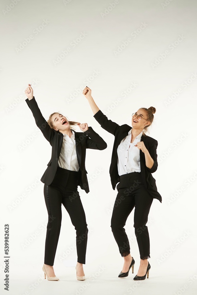 Two girls in office clothes are dancing. Pure white background. The concept of business and corporate relationships in the enterprise. Two girls in office clothes are dancing. Pure white background. The concept of business and corporate relationships in the enterprise.