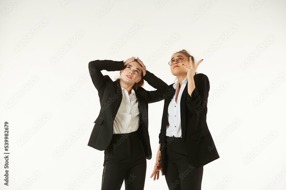 Two girls in office clothes are thinking about a project. Pure white background. The concept of business and corporate relationships in the enterprise. Two girls in office clothes are thinking about a project. Pure white background. The concept of business and corporate relationships in the enterprise.