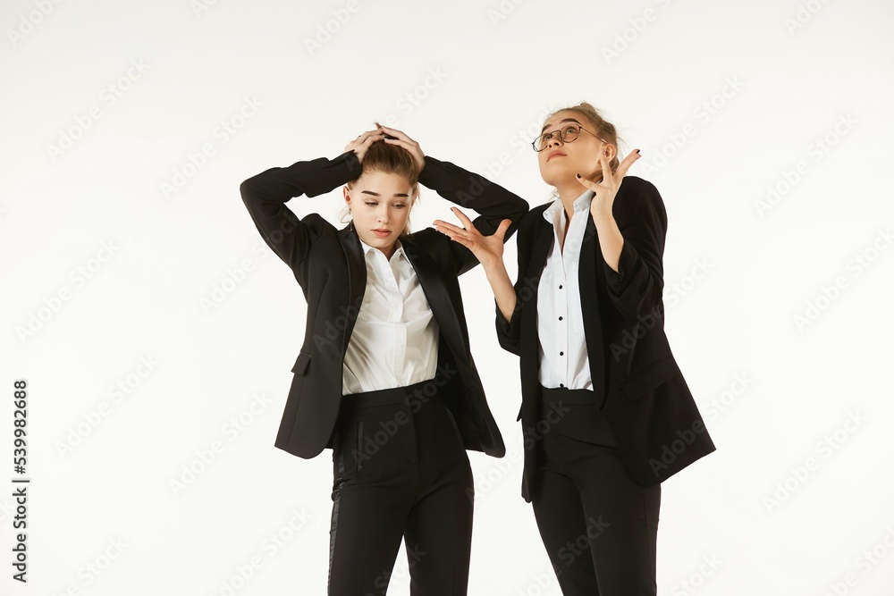 Two girls in office clothes are thinking about a project. Pure white background. The concept of business and corporate relationships in the enterprise. Two girls in office clothes are thinking about a project. Pure white background. The concept of business and corporate relationships in the enterprise.