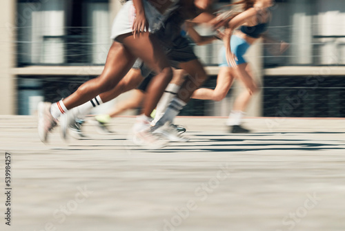 Running, motion and group of people on path together for marathon race, fitness and speed. Fast run team, urban runner club and racing in city street training workout with feet and legs on ground. photo