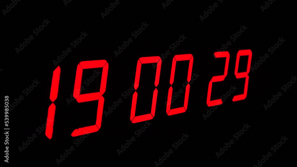 Digital timer on a black background. Light panel with red numbers