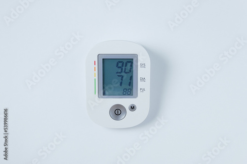 Electric blood pressure monitor with digital display. White background. Medical equipment.