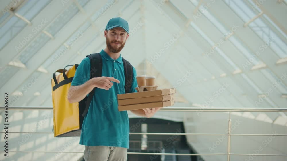 Portrait of Smiling Man Courier Delivery Standing With a Thermal Backpack and Pizza Boxes and Coffee Looking at Camera and Showing Thumb Up. Positive Deliveryman Worker Deliver Online Order Client. Portrait of Smiling Man Courier Delivery Standing With a Thermal Backpack and Pizza Boxes and Coffee Looking at Camera and Showing Thumb Up. Positive Deliveryman Worker Deliver Online Order Client.