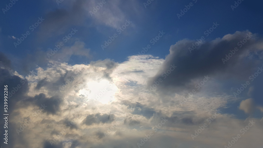 Sun behind the clouds on sky background