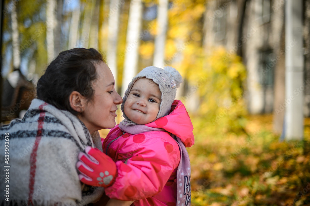 young mom with little daughter in the park in autumn close-up young mom with little daughter in the park in autumn close-up