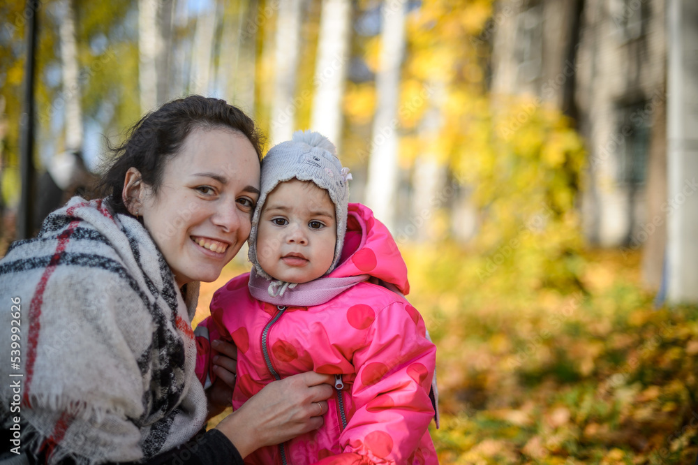young mom with little daughter in the park in autumn close-up