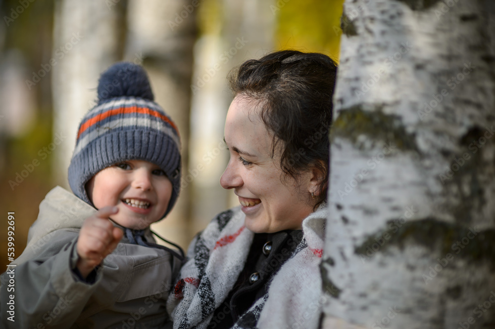 Obraz premium Happy young mother with a young son in her arms in an autumn park - close-up