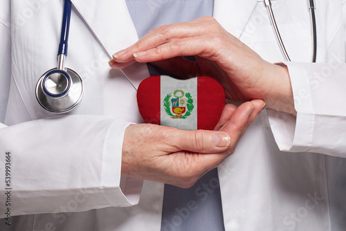 Peruvian doctor holding heart with flag of Peru background. Healthcare, charity, insurance and medicine concept photo