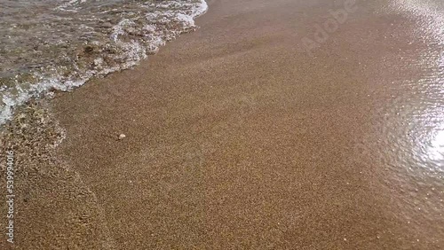 Slow motion of small sea waves on the sandy beach