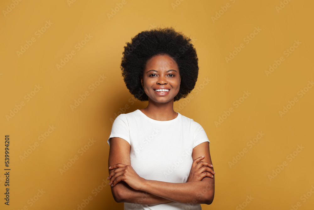 Cute attractive young woman in empty white t-shirt standing with crossed arms and smiling on bright yellow background - obrazy, fototapety, plakaty 
