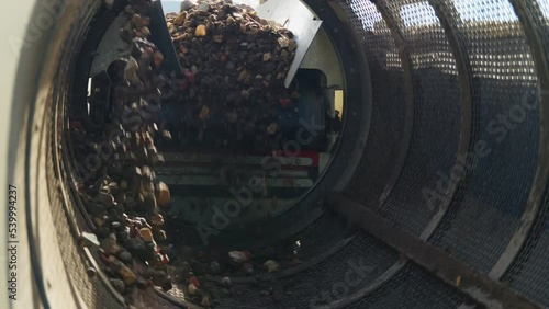 Stones Mechanical Screening - gravel with soil and sand falls from the belt conveyor to spinning cylindrical sifter with holes  sifting of soil, crushed stone and other loose building materials