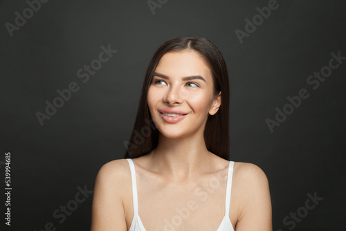 Cute female face. Pretty woman looking up and smiling on black background