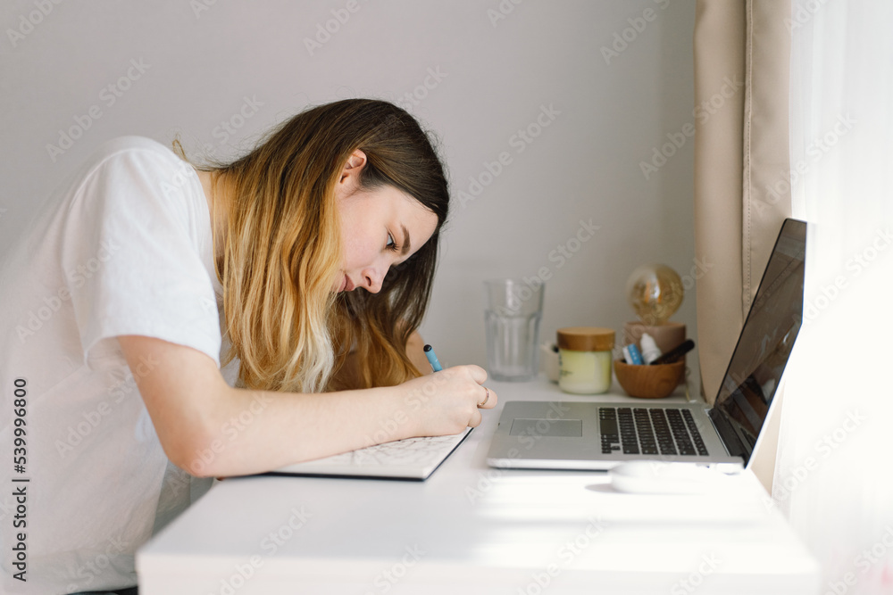A teenage girl is drawing or doing homework in the bedroom. A teenager studies at home. Back to school A teenage girl is drawing or doing homework in the bedroom. A teenager studies at home. Back to school