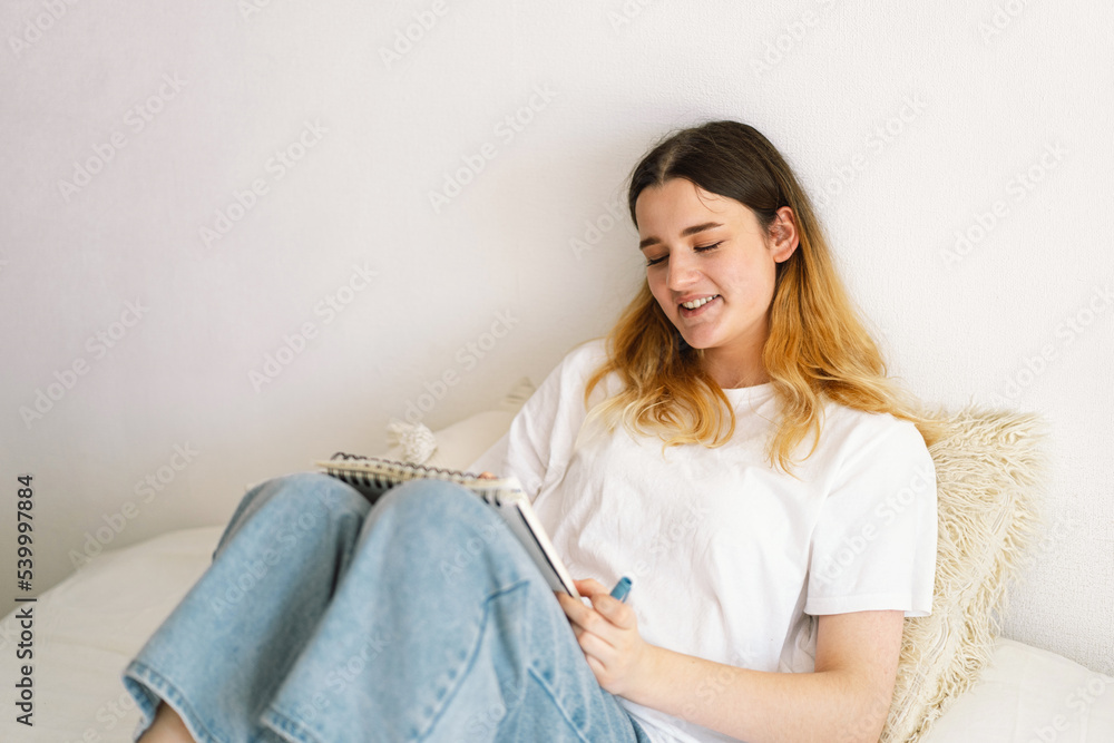 A teenage girl is drawing or doing homework in the bedroom. A teenager studies at home. Back to school A teenage girl is drawing or doing homework in the bedroom. A teenager studies at home. Back to school