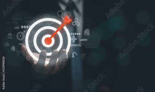 Businessman showing dart board and arrows with icons on hand, concept of targeting the business with strategy or planning for best business results. copy space.