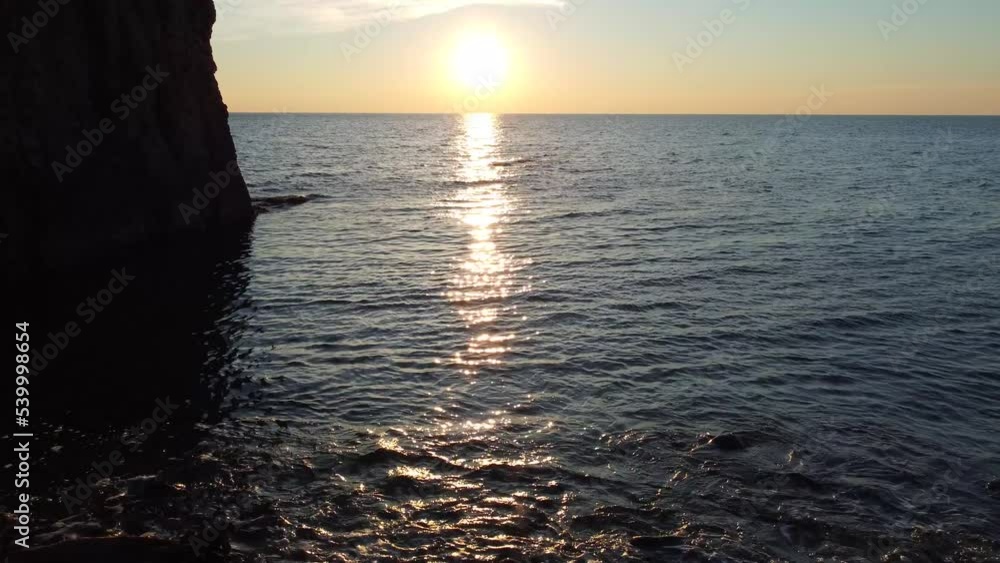 Coastline of rocky shore and blue sea at sunset, drone flight Coastline of rocky shore and blue sea at sunset, drone flight