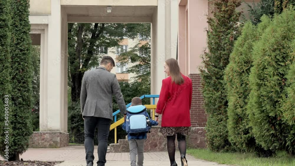 Mom and dad, parents take the child to school, see off and say goodbye, hold hands, friendly family. Mom and dad, parents take the child to school, see off and say goodbye, hold hands, friendly family.