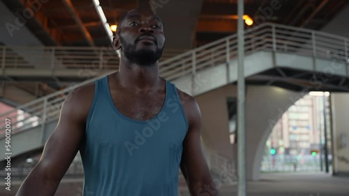 4k Young male athlete works out and jumps in city spbas. African american man doing exercise and stretching his body, getting ready for boxing training on bridge in modern town. Handsome black guy