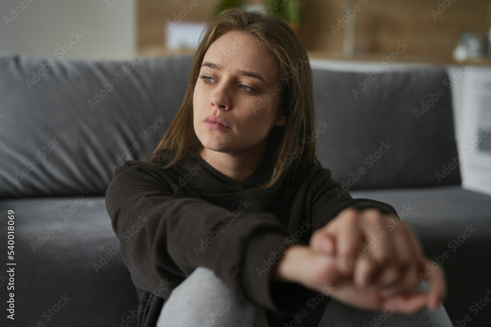 Obraz premium Caucasian sad woman sitting on the floor and looking away