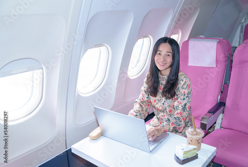  Asian young Businesswoman working using laptop compuer sitting near windows at first class on airplane during flight,Traveling and Business concept