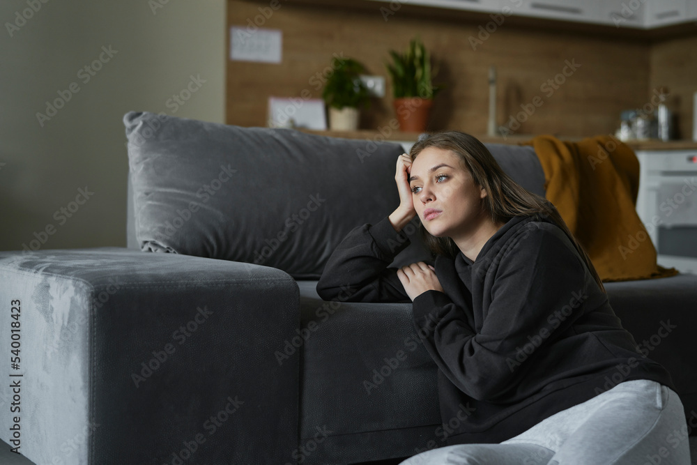 Obraz premium Caucasian sad woman sitting on the floor and looking away