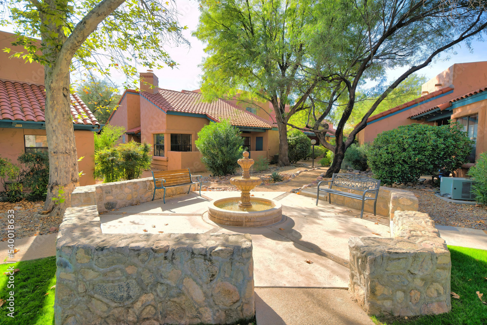 Small water fountain with two garden benches in the middle of mediterranean houses- Tucson, AZ