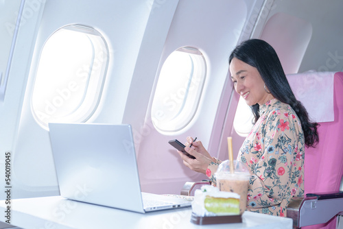  Asian young Businesswoman working using laptop compuer sitting near windows at first class on airplane during flight,Traveling and Business concept