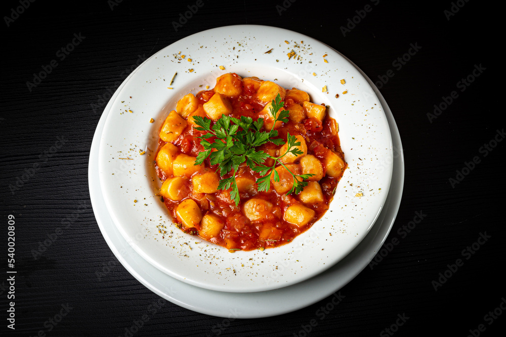 Gnocchi dish with tomato sauce and parsley on rustic wooden table. Gnocchi dish with tomato sauce and parsley on rustic wooden table.